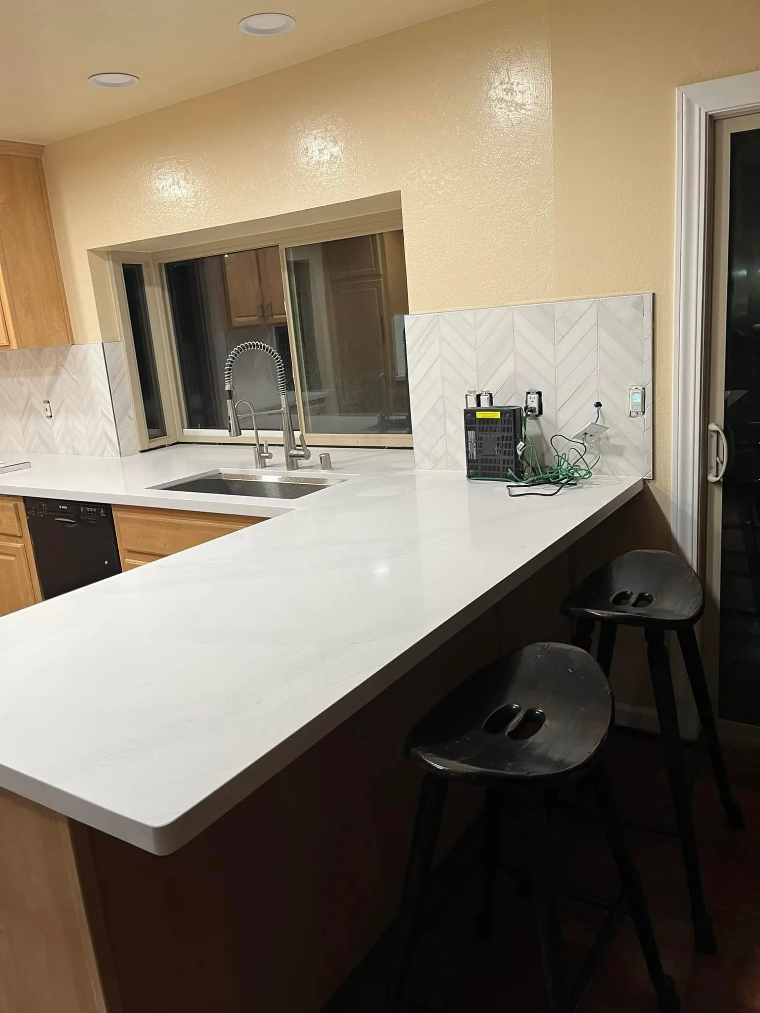 Kitchen remodel in Vallejo with a quartz peninsula and herringbone backsplash
