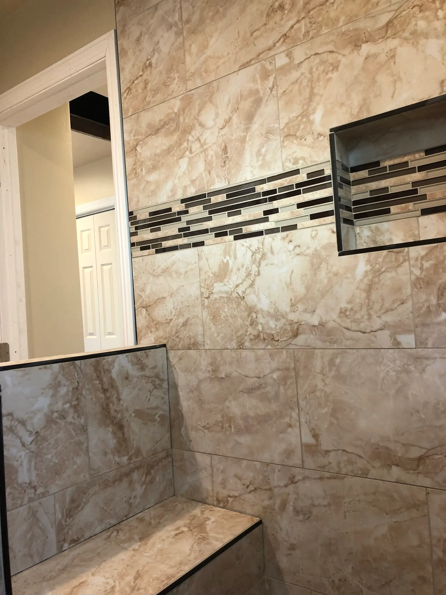Large-format tile wall with a mosaic accent strip and niche in Vallejo