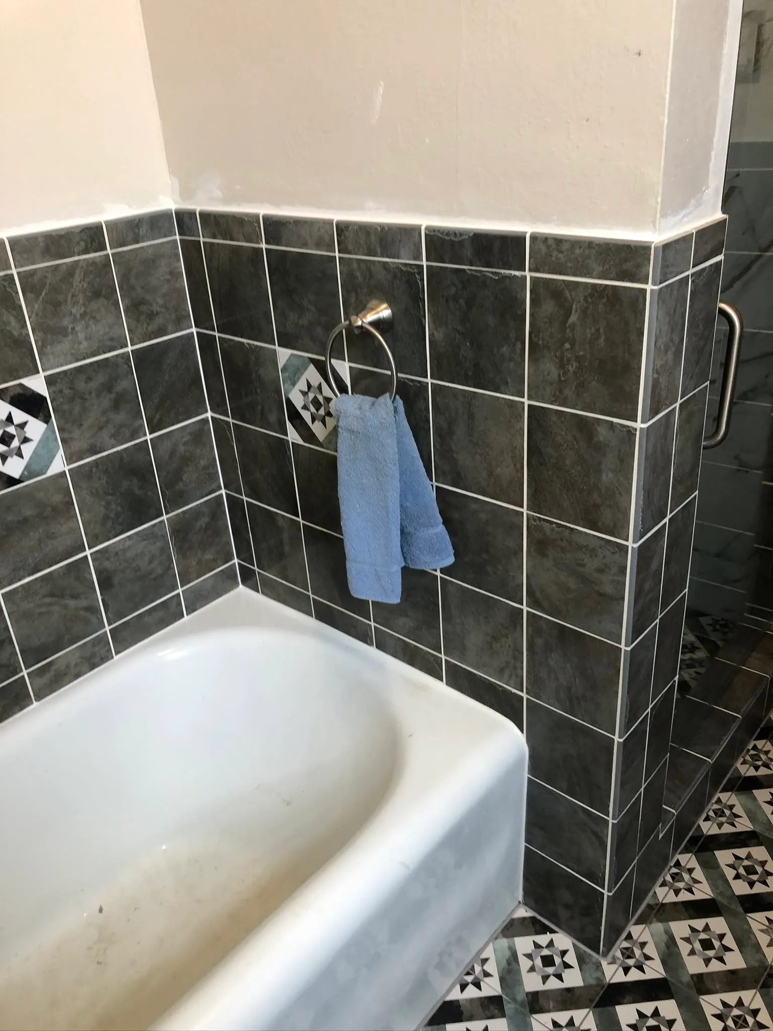 Dark tile tub surround with a patterned tile floor in a Vallejo bathroom